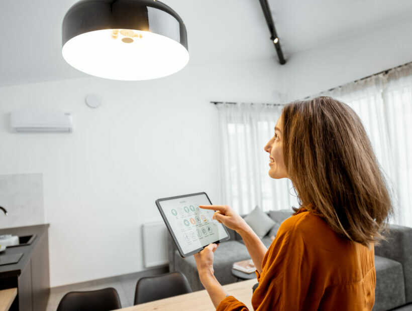 Woman controlling light with a digital tablet at home Young woman controlling home light with a digital tablet in the living room. Concept of a smart home and light control with mobile devices