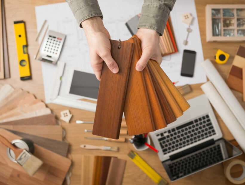 Interior designer choosing a baseboard Professional interior designer holding wood swatches for baseboard and skirting, hands close up with desktop on background